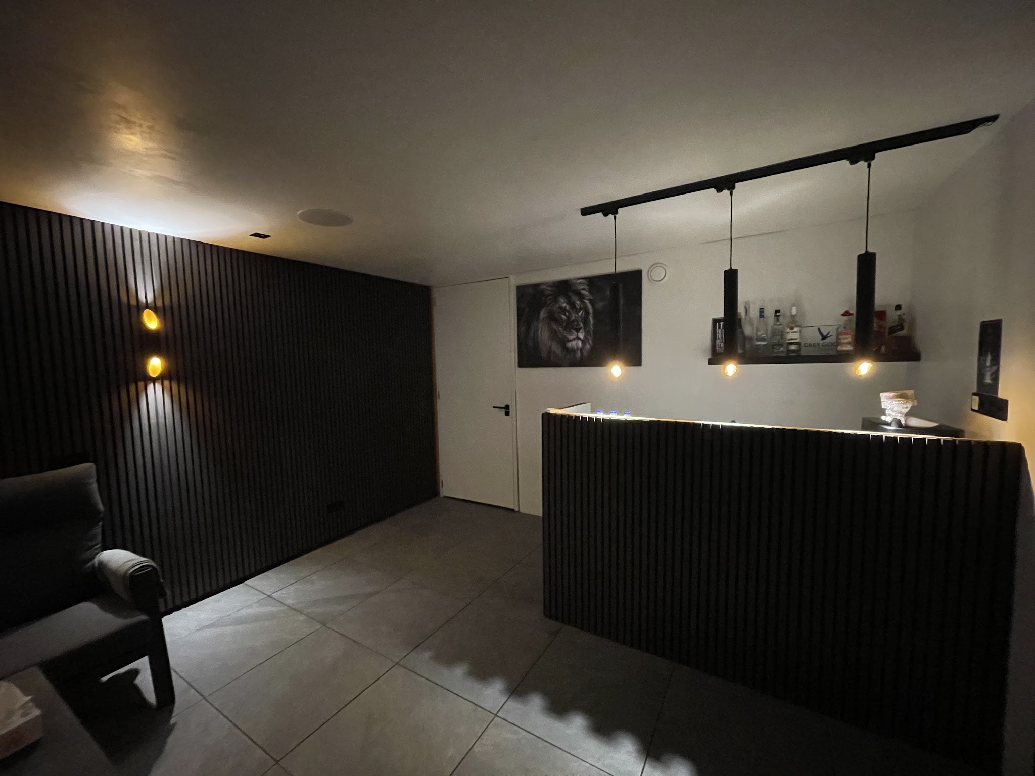 Interieur met hanglampen boven de bar en wandverlichting langs de latten