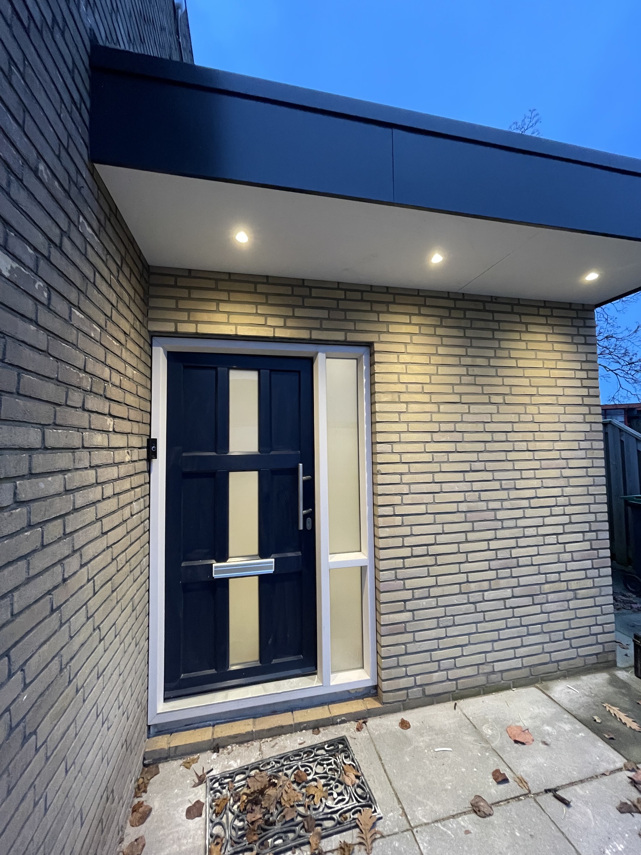 Voordeur met inbouwspots in de overkapping